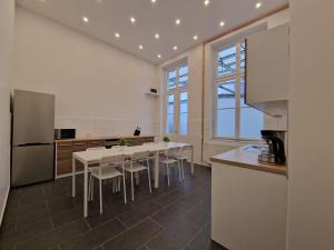 RAJ Living - 300m2 Loft with 7 Rooms - 15 Min Messe DUS & Old Town DUS في دوسلدورف: مطبخ مع طاولة وكراسي وثلاجة