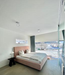 1 dormitorio con cama grande y ventana grande en Kaps Wohnen en Saalfelden am Steinernen Meer