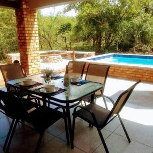 una mesa y sillas en un patio con piscina en Sonador Bush House, en Marloth Park