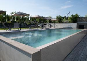 a swimming pool with tables and chairs and umbrellas at Ca' del Profeta Relais & Spa in Montegrosso dʼAsti