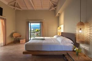 Diapori Suites Hotel في كارداميلي: غرفة نوم بسرير كبير ونافذة كبيرة