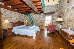 1 dormitorio con 1 cama blanca en una pared de piedra en Casa Tenada en Robledo