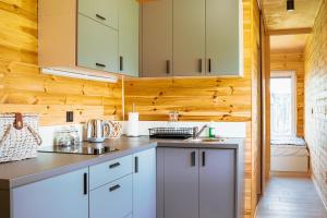 cocina con armarios blancos y paredes de madera en Arche Siedlisko Celiny, en Celiny