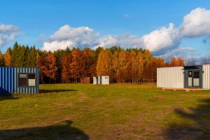 two buildings in a field with trees in the background at Arche Siedlisko Celiny in Celiny