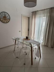 une table et des chaises en verre dans une pièce avec une horloge dans l'établissement MATTIA'S HOME, à Caserte