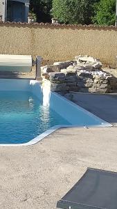 a swimming pool in a yard with a stone wall at Location en nuitée in Abeilhan