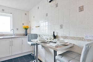 cocina con mesa, sillas y fregadero en Elegance Graceland en Gillingham