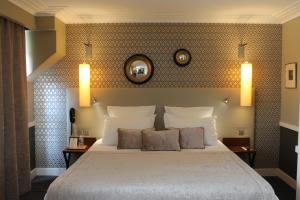 una camera da letto con un grande letto bianco con due lampade di Hôtel jardin Le Pasteur a Chalons en Champagne