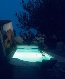 - une piscine éclairée dans une cour la nuit dans l'établissement Aux portes des iles, à Saint-Just