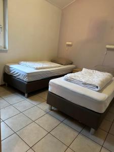 two twin beds in a room with tile floors at Recreatiebungalow Lochem in Lochem