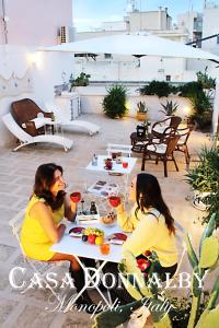 Due donne sedute a un tavolo su un patio di Casa Donnalby a Monopoli