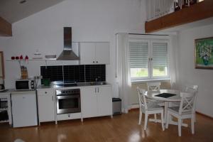 - une cuisine avec des placards blancs, une table et des chaises dans l'établissement Ferienwohnung Nett, à Blankenheim