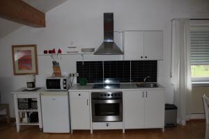 La cuisine est équipée de placards blancs et d'un four avec plaques de cuisson. dans l'établissement Ferienwohnung Nett, à Blankenheim