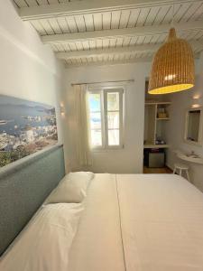 a bedroom with a large white bed with a window at Lefteris in Mikonos