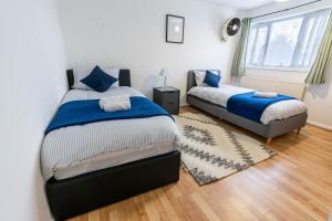 a bedroom with two beds and a window at 3 Bedroom house with free parking, Dalstone,Aylesbury in Buckinghamshire