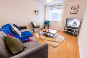 a living room with a couch and a tv at 3 Bedroom house with free parking, Dalstone,Aylesbury in Buckinghamshire