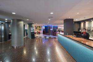 a man sitting at a counter in a lobby with a laptop at Catalonia Park Putxet in Barcelona