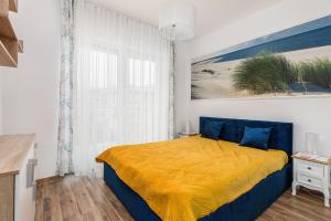 1 dormitorio con 1 cama con manta amarilla en Apartament Holiday 8/25 en Rewal