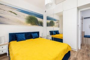 a bedroom with a yellow bed with blue pillows at Apartament Holiday 8/25 in Rewal +42 photos