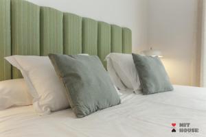 uma cama com almofadas brancas e uma cabeceira verde em Bellas Artes en Madrid em Madri