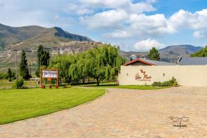 a building with a sign in a field with mountains in the background at WILLOW MANOR in Clarens