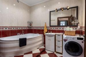 y baño con bañera y lavadora. en Lovely 2-bdrm condo ideal for couples and family with children, free parking on premises en Riga