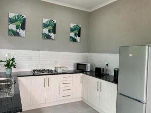 a kitchen with white cabinets and a refrigerator at Hazyview Accommodation, Bon Repose Cottages 3&4 in Hazyview