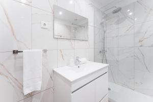 La salle de bains blanche est pourvue d'un lavabo et d'une douche. dans l'établissement GuestReady - Amazing stay near Cedofeita Church, à Porto