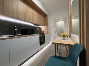 uma cozinha com uma mesa e uma cadeira azul em Perfect Host Palas Centru em Iaşi