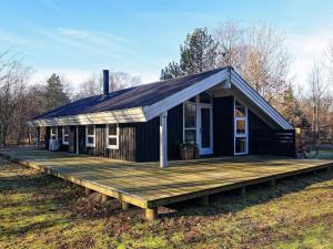 a small black house with a wooden deck at Holiday home Hals CXLI in Hals