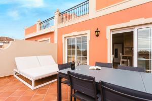 een patio met een tafel en stoelen en een gebouw bij luxury duplex apartment with beautiful sea views in Palm-mar