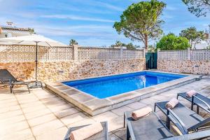 a swimming pool with two chairs and an umbrella at Villa Monsy 1 in El Port