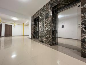 a lobby with a marble wall and a elevator at Perfect Host Palas Centru in Iaşi