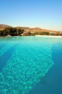 uma grande piscina de água azul em frente a uma praia em Villa Laguna Blu em Kampos Paros