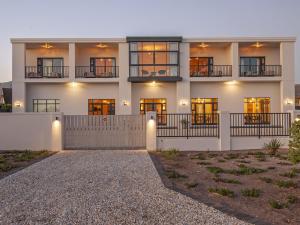 a large white building with windows and a driveway at Glow Boutique Suites & Guesthouse in Hermanus