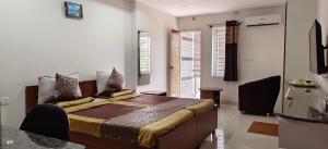 een slaapkamer met een bed in een kamer met ramen bij Sugamya Corner Guesthouse in Mysore