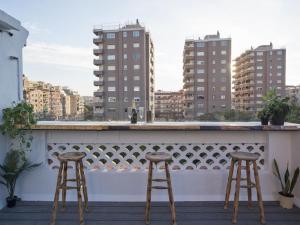 two bar stools on a balcony with buildings at BCN: ¡Exclusivos y cerca del Camp Nou! in El Arrabal