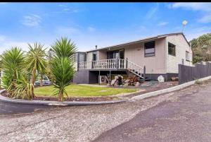 una casa con palmeras delante en Mountain Top kiwi star holiday home en Rotorua
