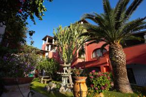 un giardino con palme e fiori di fronte a un edificio di Residence Hotel Villa Fiorentino a Città di Lipari