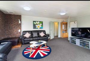 a living room with a couch and a tv at Mountain Top kiwi star holiday home in Rotorua