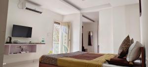 ein Schlafzimmer mit einem Bett und einem TV in der Unterkunft Sugamya Corner Guesthouse in Mysore