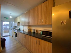 een keuken met houten kasten en een zwart aanrecht bij Nice Living Serviced Accommodations 4 in Coventry