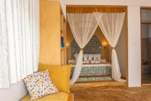 a bedroom with a bed with curtains and a couch at Nungwi Garden Boutique Hotel in Nungwi