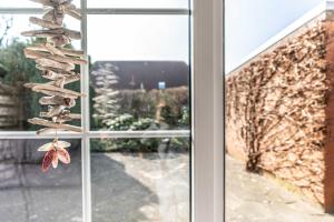 uma janela com um monte de conchas penduradas em Ferienhaus Förster, FeWo Vermittlung Nordsee em Dangast