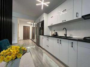 a kitchen with white cabinets and a vase of yellow flowers at Perfect Host Palas in Iaşi