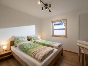 1 dormitorio con 2 camas y ventana en Berg Apartment Barbara, en Hopfgarten im Brixental