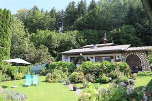 ein Haus mit einem Garten mit zwei Stühlen und einem Sonnenschirm in der Unterkunft Ferienwohnung Schellander Privatstrand in Velden am Wörthersee