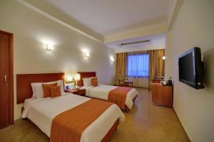 um quarto de hotel com duas camas e uma televisão de ecrã plano em Royal Sarovar Portico Siliguri em Siliguri