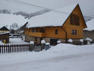 ein schneebedecktes Haus mit einem Zaun in der Unterkunft Chalupa Praženica in Liptovské Revúce