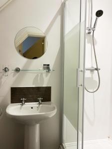 a white bathroom with a sink and a mirror at Painters at the Angel in Sudbury